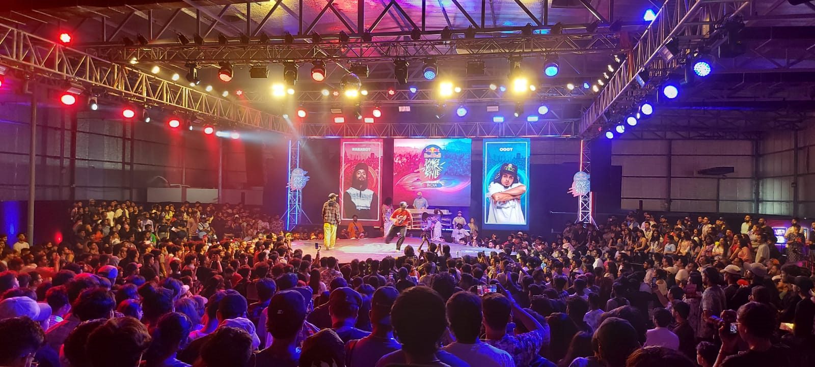Wide concert crowd lit by warm stage lighting inside a large venue