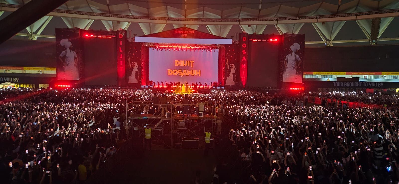 Arena crowd holding up phone lights during a Dil-Luminati Tour show