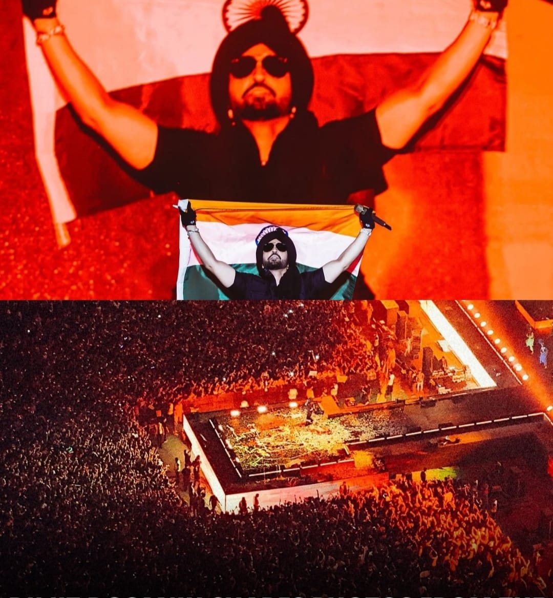 Artist performing on stage draped in the Indian flag under red lights on the Dil-Luminati Tour
