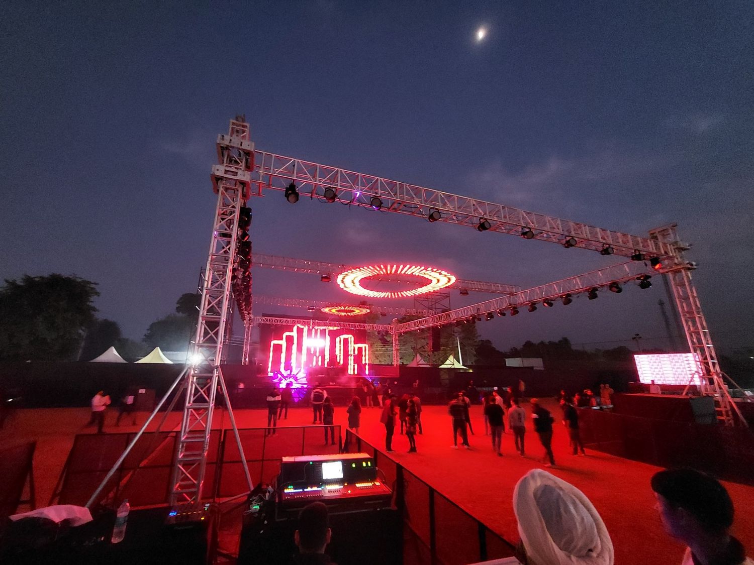Red-lit event structure with a circular stage element at dusk