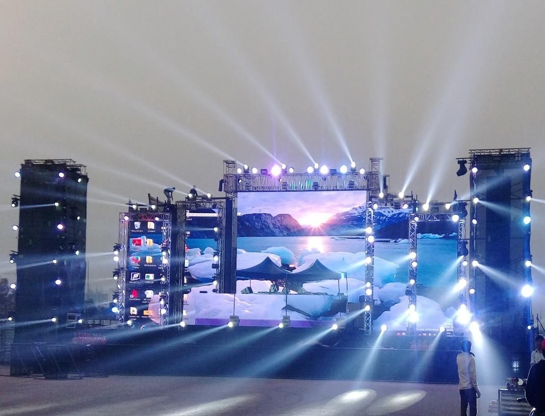 Outdoor concert stage with layered lighting rig and sound towers