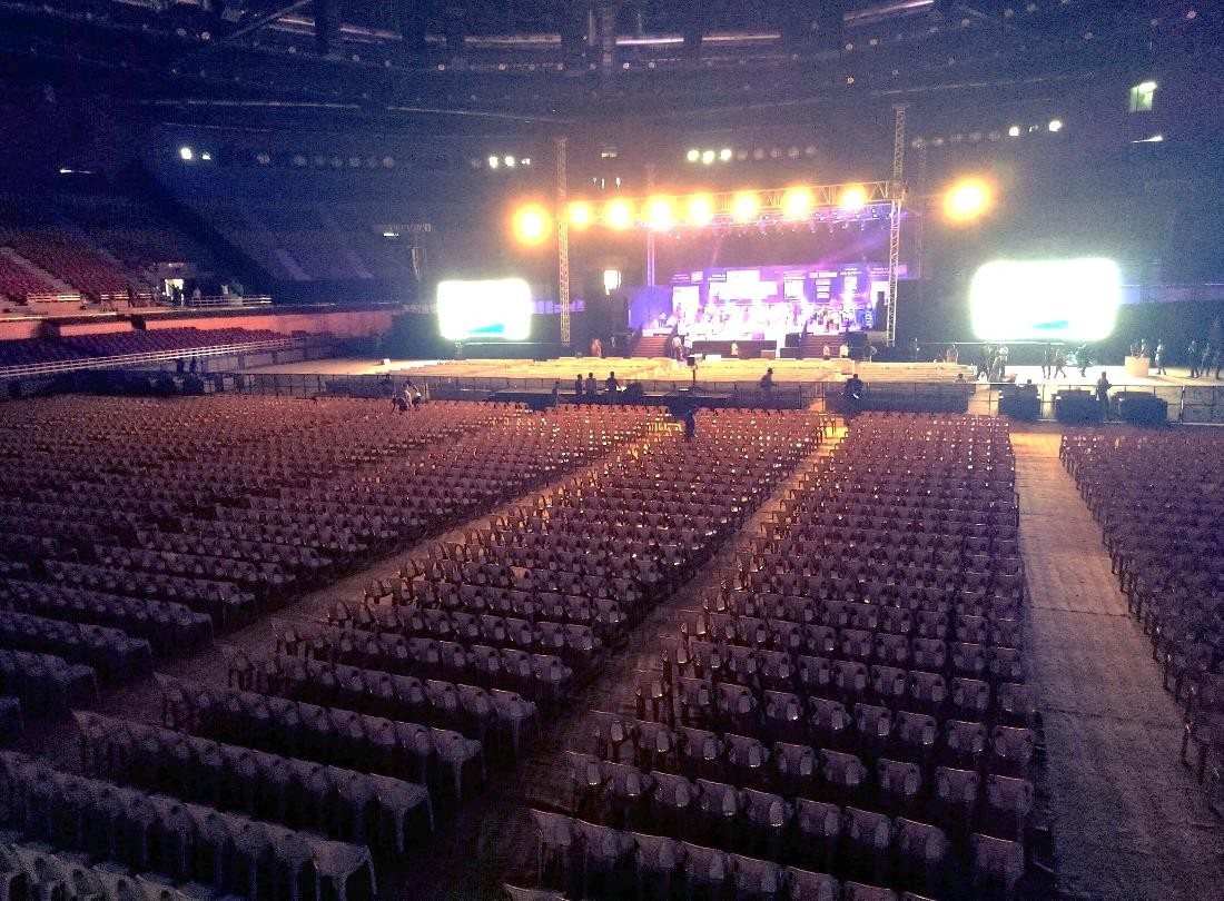 Stadium concert stage viewed across empty tiered seating
