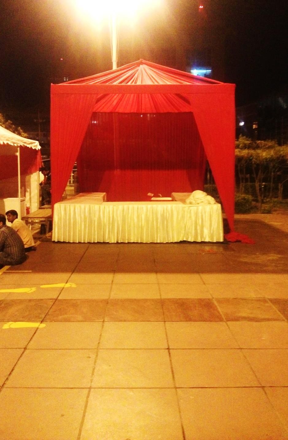 Red fabric cabana tent with gold-draped seating lit at night