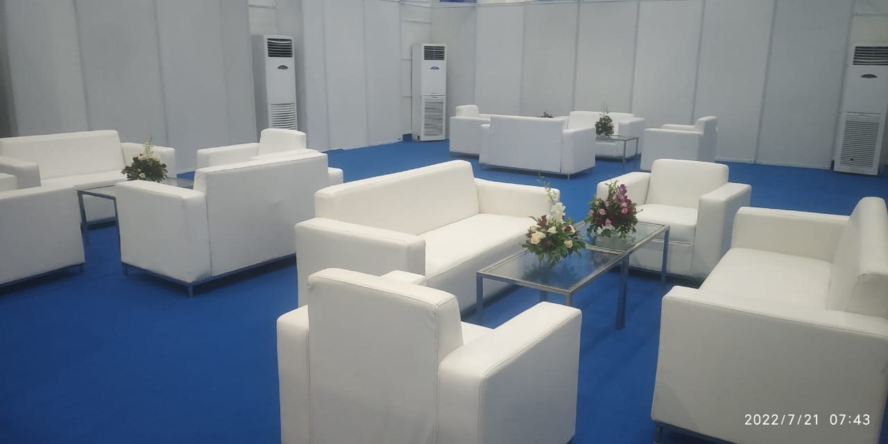 White lounge sofa sets arranged on blue carpet with a floral centrepiece