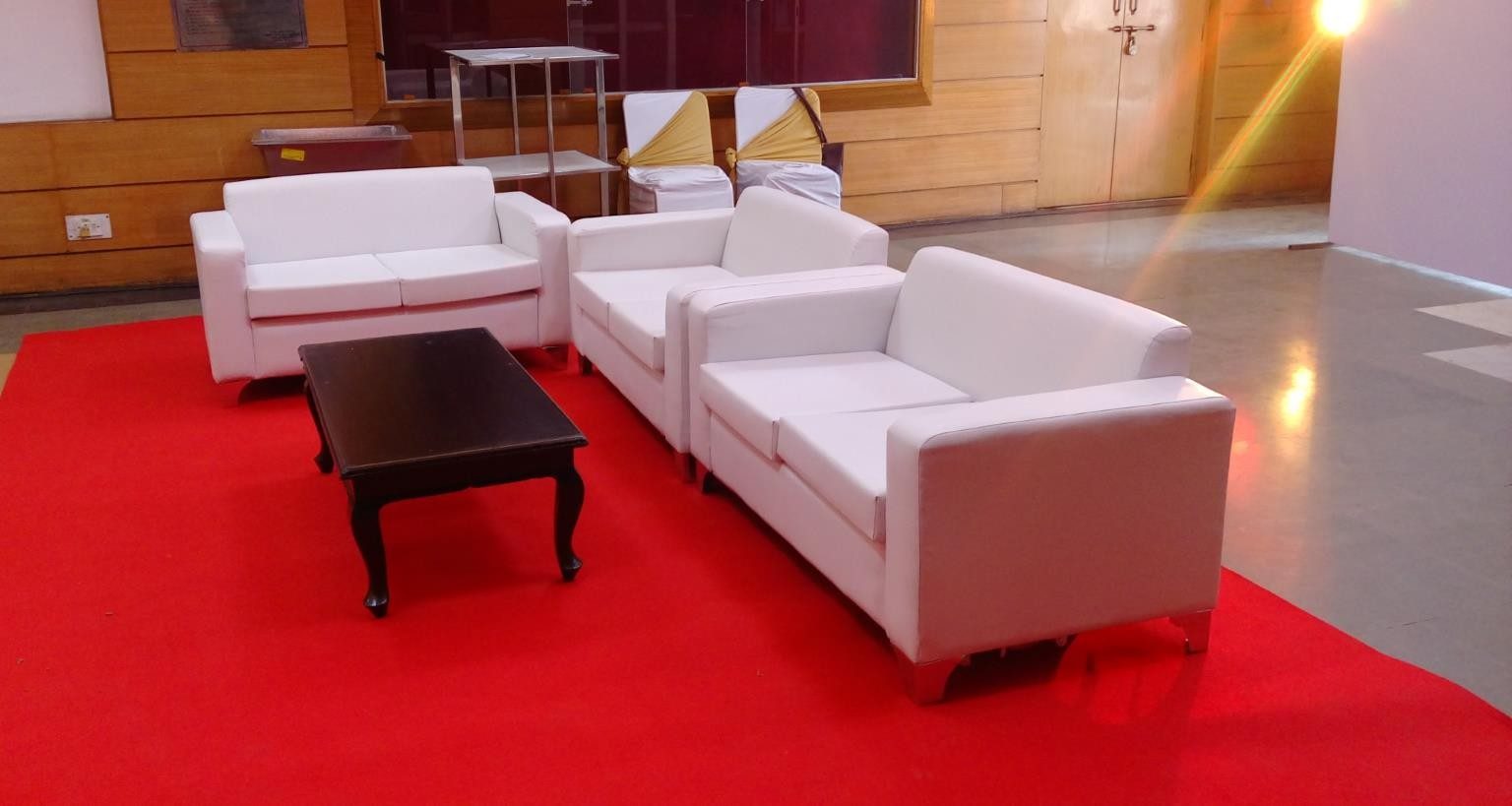 White upholstered VIP lounge seating arranged on a red carpet