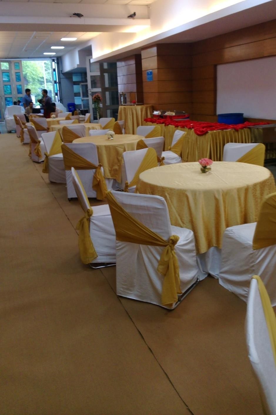 Indoor banquet hall with round tables dressed in gold and white linen