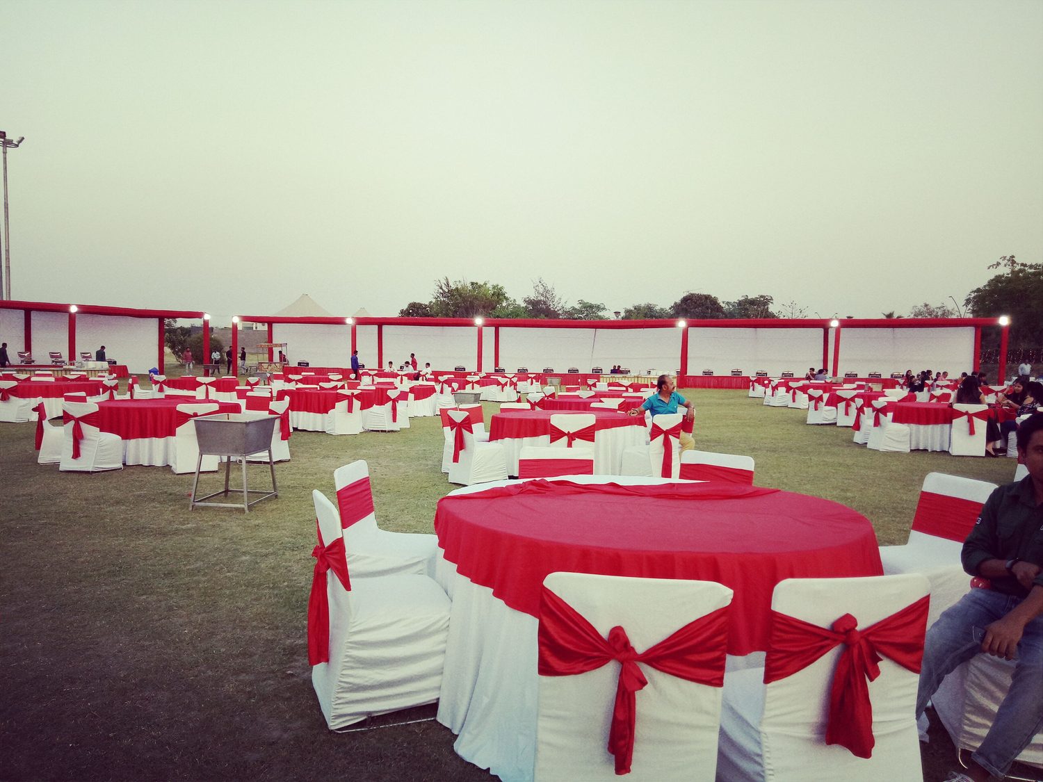 Outdoor banquet with round tables in red linen and white chair covers
